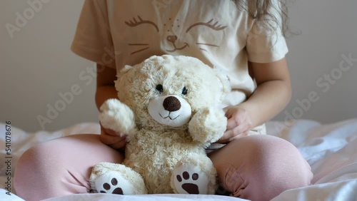 A little girl plays with a teddy bear. Childhood and toys.