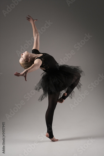Ballerina Dancing with tutu Modern Ballet Dancer in dancer tutu, Gray Background. Dancer in Black clothes showing her flexibility posing on gray background in studio