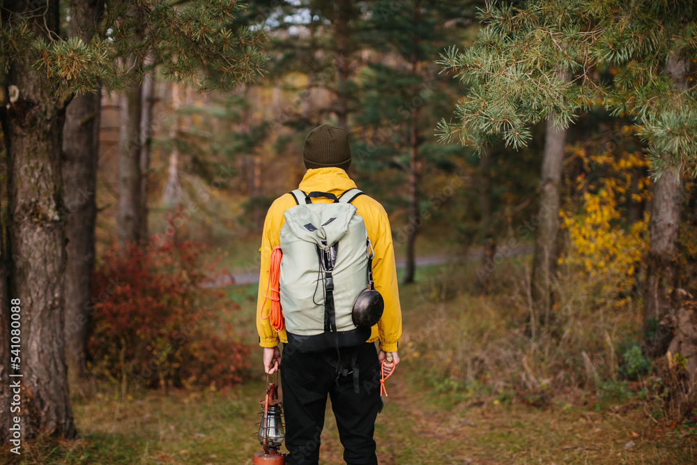 Tourist on a hiking trail in the forest with a backpack and a lamp.