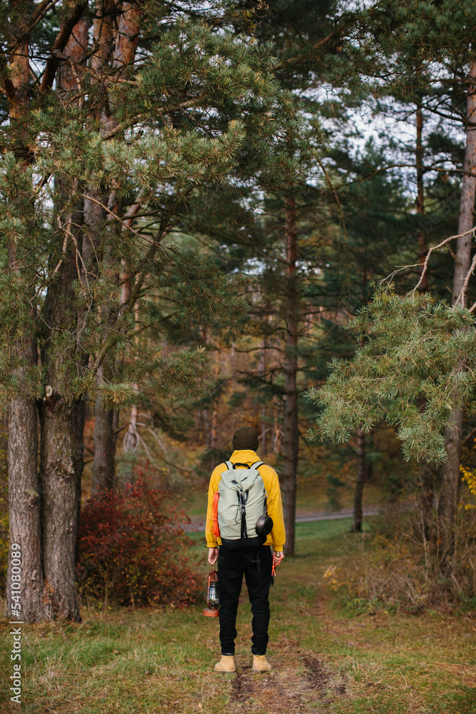 Fototapeta premium Tourist on a hiking trail in the forest with a backpack and a lamp.