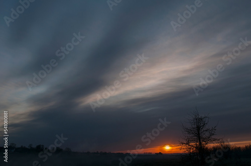 Panorama of dawn fire in the sky above the natural pasture. Golden red clouds just before sunrise. Picturesque landscape at sunrise. Beauty in nature © mikhailgrytsiv