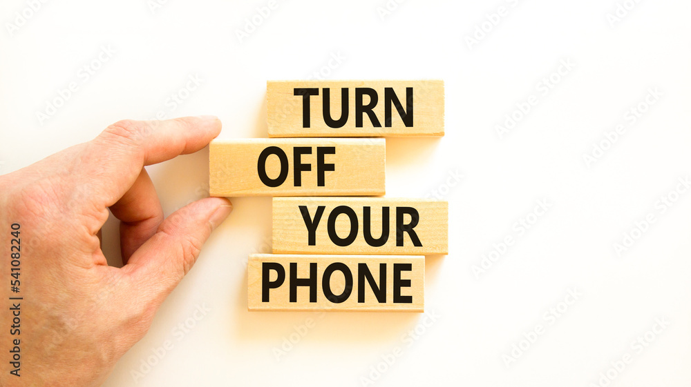 Turn off your phone symbol. Concept words Turn off your phone on wooden blocks. Beautiful white table white background. Businessman hand. Business psychological turn off your phone concept. Copy space