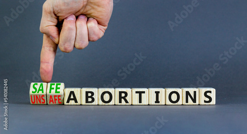 Safe or unsfe abortions symbol. Concept words Safe abortions and Unsfe abortions on wooden cubes. Doctor hand. Beautiful grey background. Medical safe or unsfe abortions concept. Copy space. photo