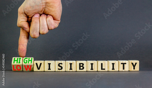 High or low visibility symbol. Concept words High visibility and Low visibility on wooden cubes. Businessman hand. Beautiful grey background. Business high or low visibility concept. Copy space.
