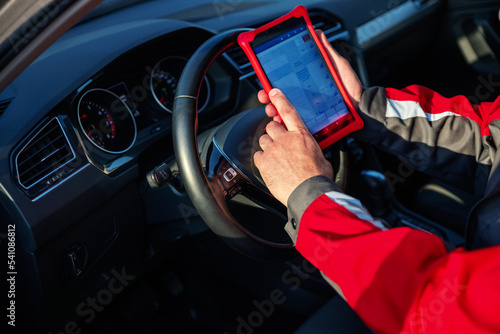 Car mechanic holds tablet for checking the electronic systems of cars