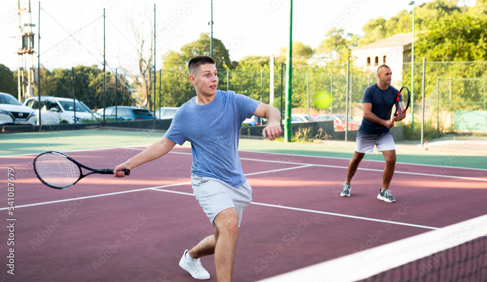 Obraz premium Sports active man during friendly doubles couple match. Two men playing together tennis outdoor
