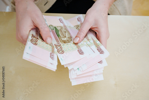 a woman holds in her hands and recalculates Russian banknotes of 100 rubles. 