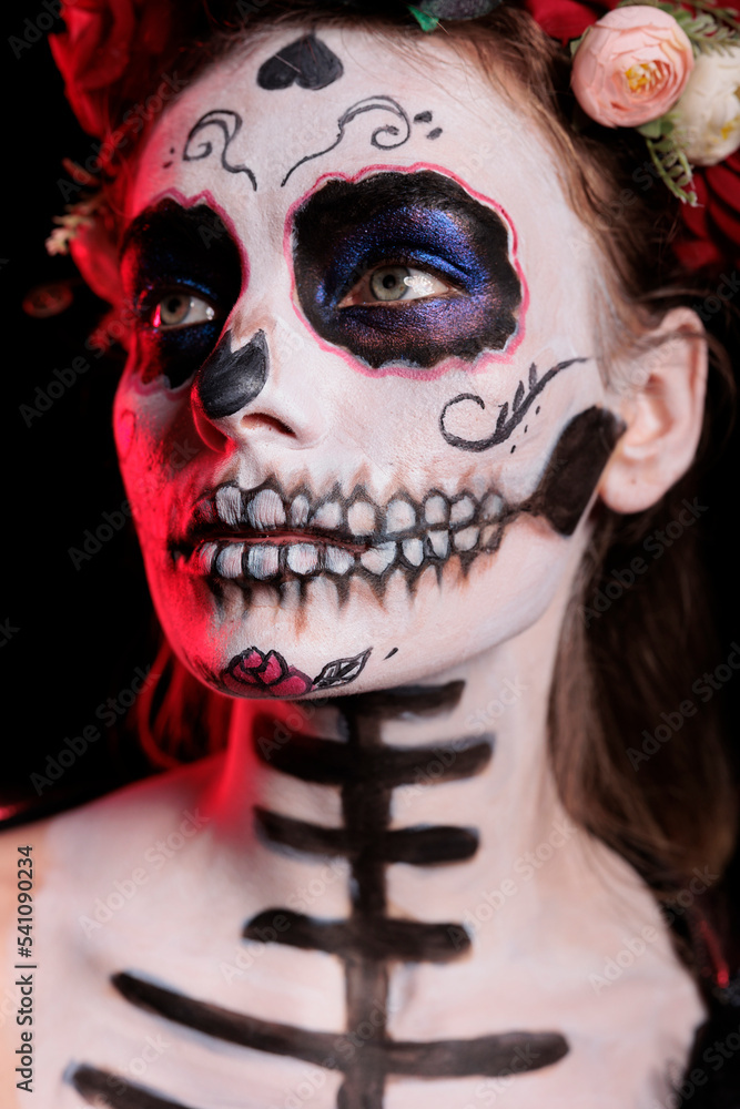 Studio shot of glamorous woman with skull make up, portraying holy santa muerte lady of death on dios de los muertos holiday. La cavalera catrina body art with black costume and flowers. Studio shot of glamorous woman with skull make up, portraying holy santa muerte lady of death on dios de los muertos holiday. La cavalera catrina body art with black costume and flowers.