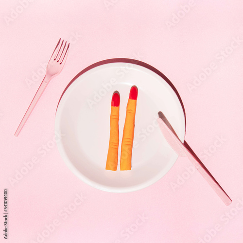 Spooky Halloween concept. Creepy witch fingers in plate on light pink background. Creative festive idea. Minimalistic holiday and food composition.