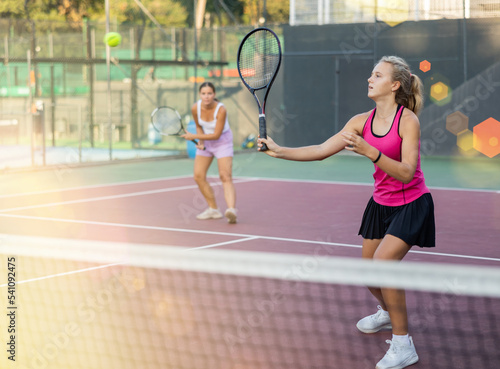 Young woman in skirt playing tennis on court. Racket sport training outdoors. © JackF