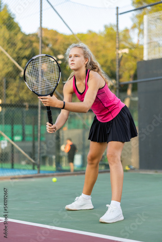 Caucasian young woman in tank top and skirt playing tennis match during training on court. © JackF