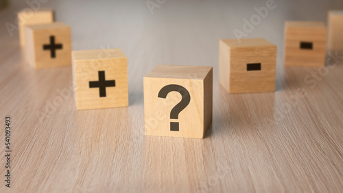 sign question mark, plus, minus sign on the faces of a wooden cube. mini wood cubes on wooden background