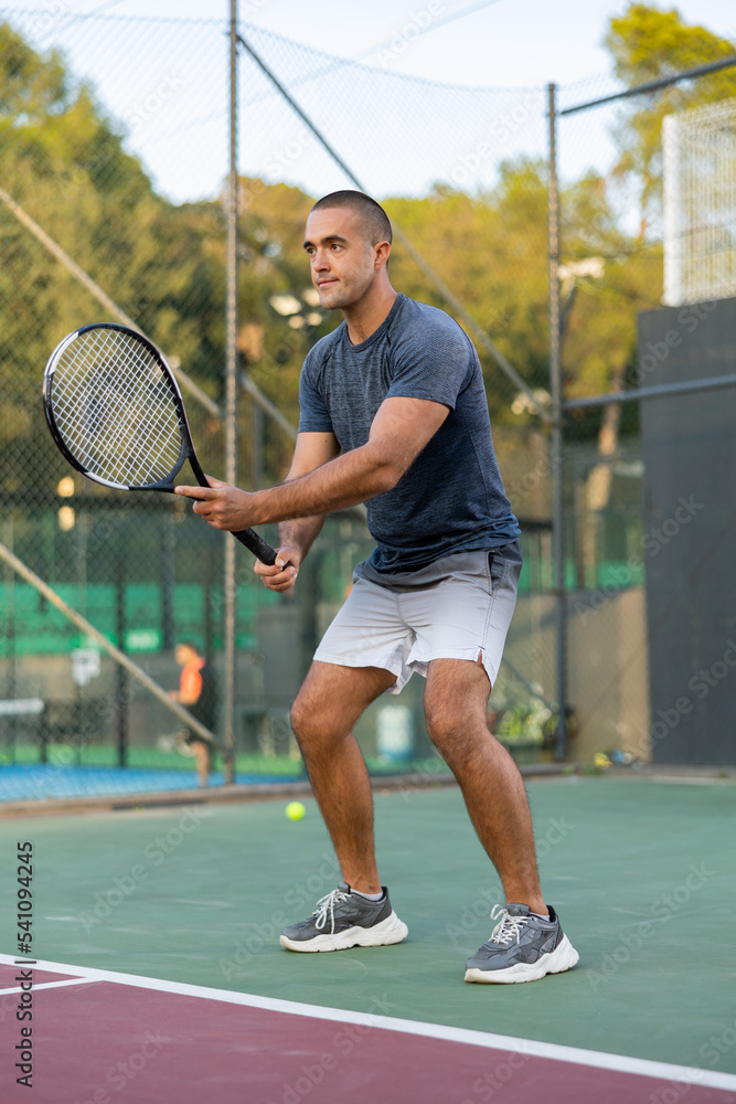 Focused man playing doubles tennis with female partners at warm sunny day, healthy lifestyle concept