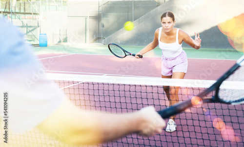Focused young woman playing friendly tennis match on court. Concept of concentration in competition