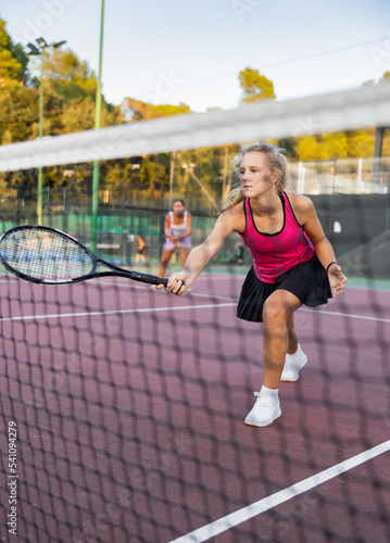Female player playing tennis in tennis court outdoor behind the net © JackF