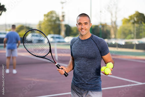 Portrait of cheerful caucasian man tennis player in outdoor court. © JackF
