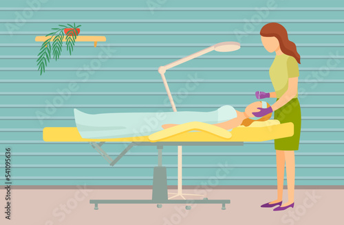 Young woman getting facial massage in spa salon. Professional masseuse and female client lying on table covered with towel. Facial procedures, body care concept. Lady during massage of face