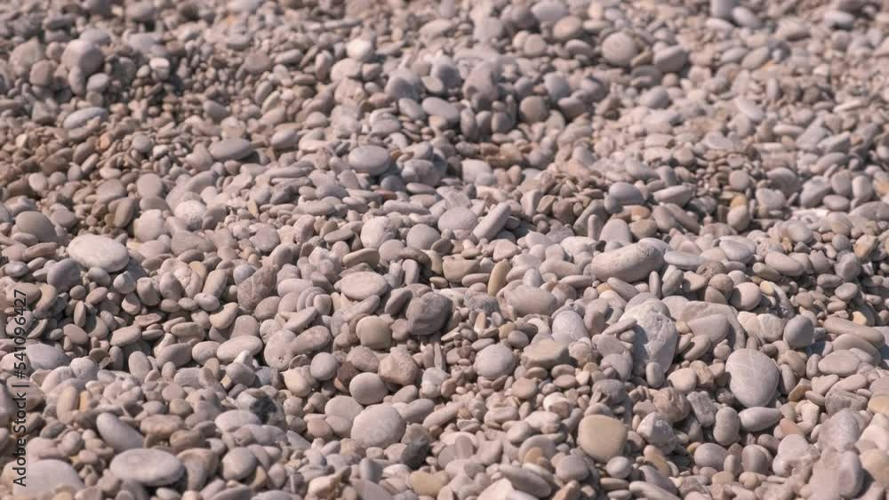 White pebble shore under sun. A view of white small pebbles laying on the sea shore under sun. White pebble shore under sun. A view of white small pebbles laying on the sea shore under sun.