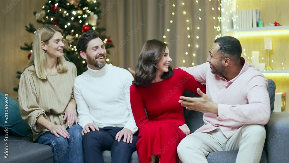 portrait cheerful friends looking at camera while sitting at home on the couch at a New Year's party or Christmas Eve. company diverse group young people smile. Guys hugging having fun portrait cheerful friends looking at camera while sitting at home on the couch at a New Year's party or Christmas Eve. company diverse group young people smile. Guys hugging having fun