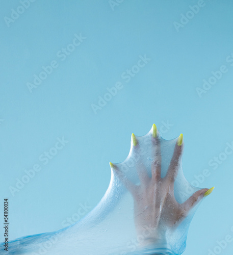 Beautiful woman's hand with yellow nail isolated on pastel blue background. Minimal aesthetic fingers concept.
