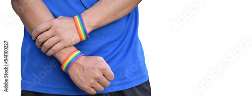Rainbow wristband on right and left hand, soft and selective focus, blurred street background.