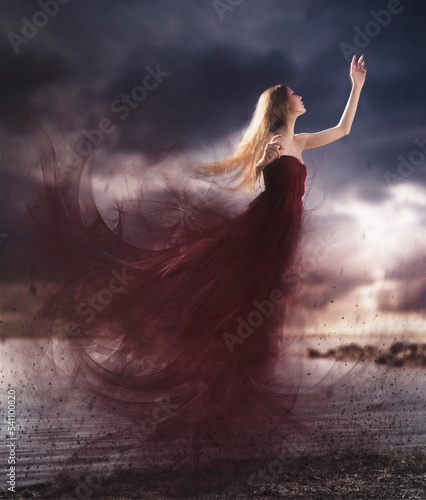 Dreamy shot of a woman in a red dress levitating up to the sky on a cloudy day.