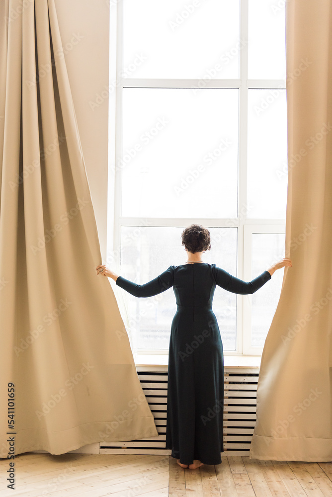 Woman by the window moving curtains Woman by the window moving curtains