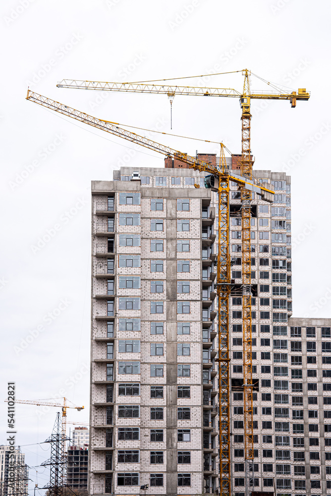 Crane and building under construction against white sky Crane and building under construction against white sky