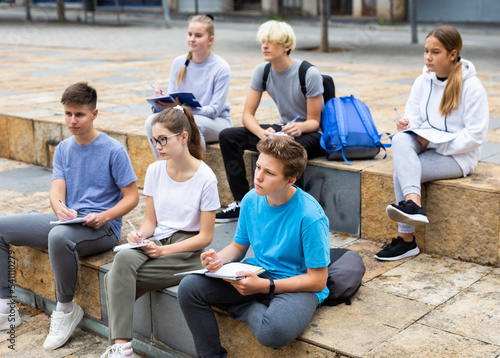 Open air lecture. Students record lecture while sitting on a stone street parapet