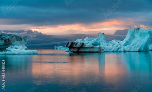 jokulsarlon glacier lagoon during sunset with orange sunlight over the cloud and reflection