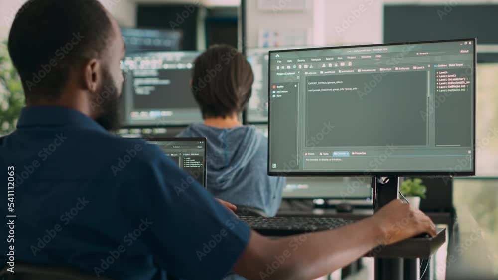 African american system engineer working on software development with source code, looking at computer. IT app developer writing ai algorithm in office, online cloud computing. Handheld shot.