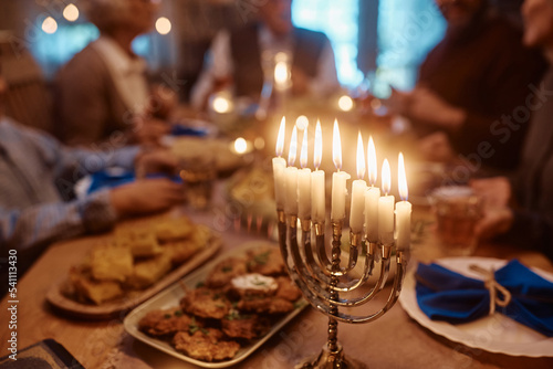 Canvas Print Close up of menorah on dining table with extended Jewish family in background