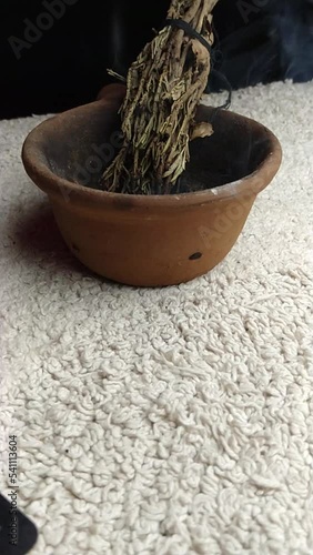 Burning sage in a bowl on white table with black background showing sage smoke photo