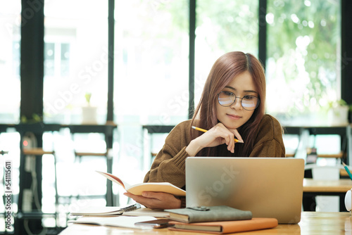 Woman learning online using laptop and writing notes.