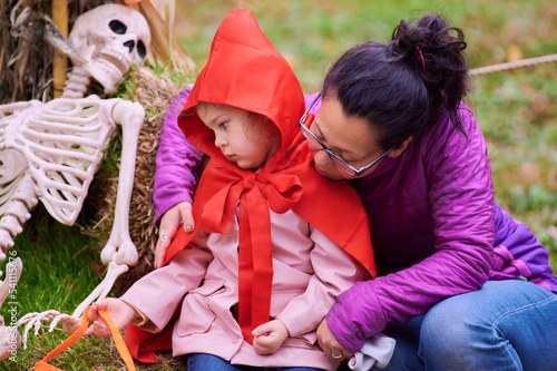 Young girl taking pictures with mom on Halloween in a red riding hood costume photo