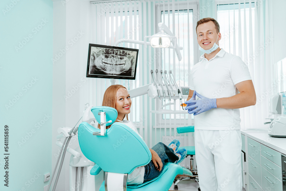 Doctor dentist and young woman patient smiling in dental clinic with medical equipment, x-ray dental, tools. Smile healthy teeth concept Doctor dentist and young woman patient smiling in dental clinic with medical equipment, x-ray dental, tools. Smile healthy teeth concept