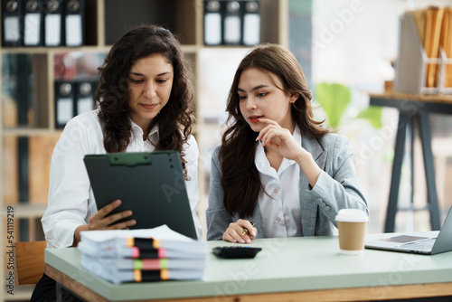 Young friendly business people are talking to each other, while sitting at the desk in a modern office. Focus on woman. Concept of business success