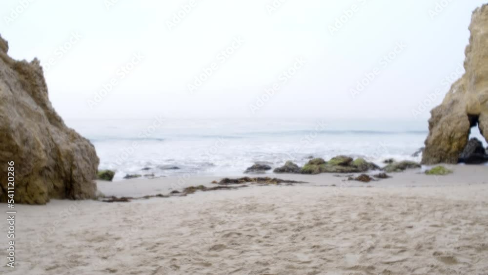 View through special effects lens of Pacific Ocean waves breaking on a sandy shore in southern California, early morning with sea mist, and rocks framing the beach View through special effects lens of Pacific Ocean waves breaking on a sandy shore in southern California, early morning with sea mist, and rocks framing the beach