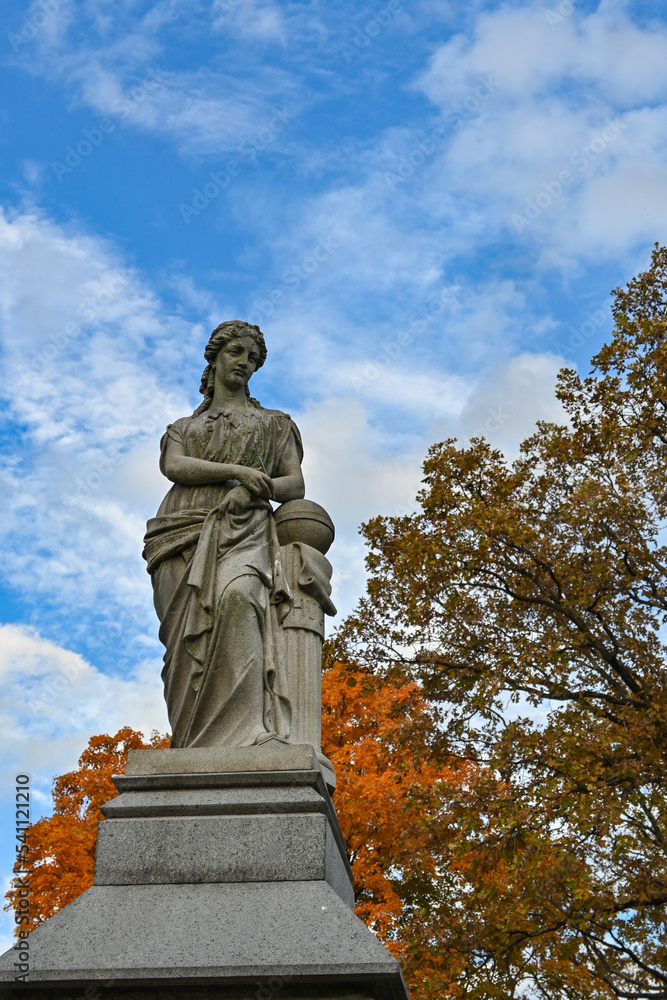 A statue of a woman in a cemetery in the autumn
