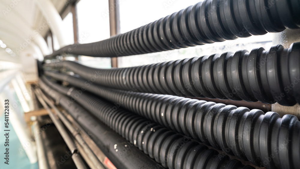 Row of electric cable protection flexible tube which are installed on factory workplace wall. Industrial equipment object photo, selective focus. Row of electric cable protection flexible tube which are installed on factory workplace wall. Industrial equipment object photo, selective focus.