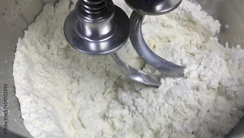 Raw dough in a bread dough mixer. Slow motion video. The process of making bread with a flour mixer. Preparation of dough in the home kitchen. Kneading dough.
