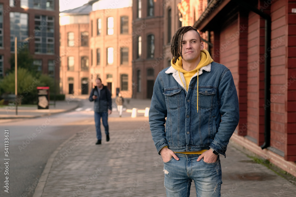 Handsome man with dreadlocks posing on city street. Positive male looking away, smiling. Handsome man with dreadlocks posing on city street. Positive male looking away, smiling.