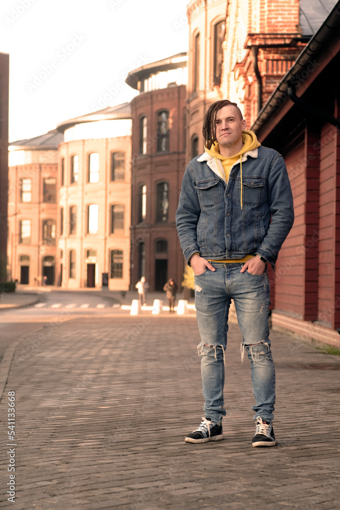 Handsome man with dreadlocks posing on city street. Positive male looking away, smiling. Handsome man with dreadlocks posing on city street. Positive male looking away, smiling.