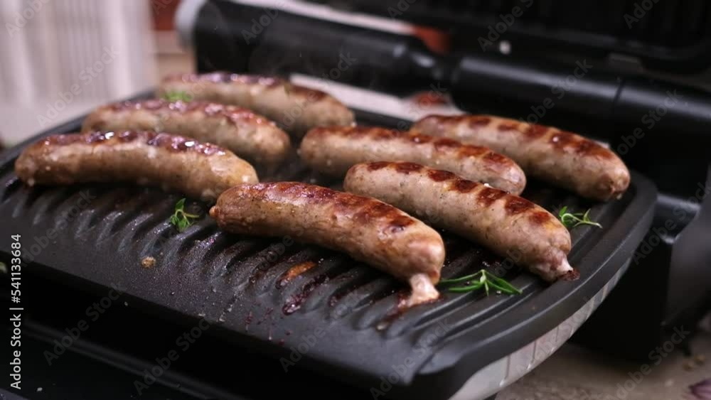 Homemade juicy pork sausages with spices frying on electric grill Homemade juicy pork sausages with spices frying on electric grill