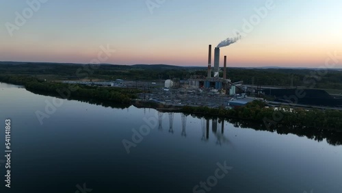 Aerial of electric power plant. Electricity generation. Smokestack factory reflection in water. Power lines. Aerial at sunset. photo