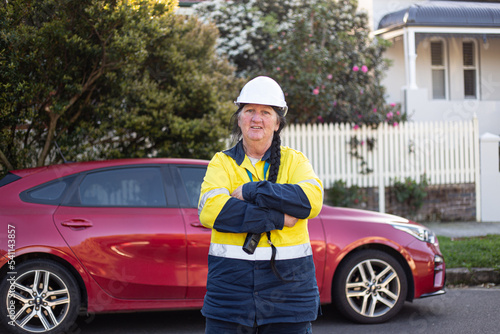 Smiling woman road worker crossing her arms in front of a red car photo