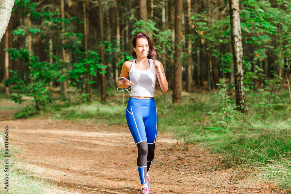 Young pretty woman running in the park at summer morning.The girl is listening to music while running.Sport and health nature concept Young pretty woman running in the park at summer morning.The girl is listening to music while running.Sport and health nature concept
