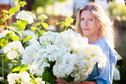 Beautiful elderly woman with a bouquet of flowers. Smiling woman in her garden.