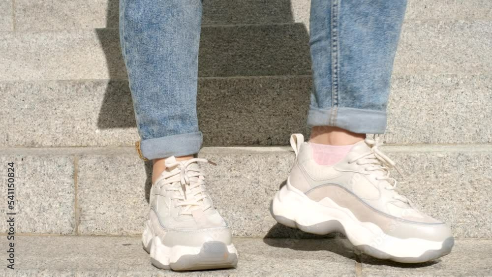 Female legs in running shoes close-up on the background of the gray stairs. Female legs in running shoes close-up on the background of the gray stairs.