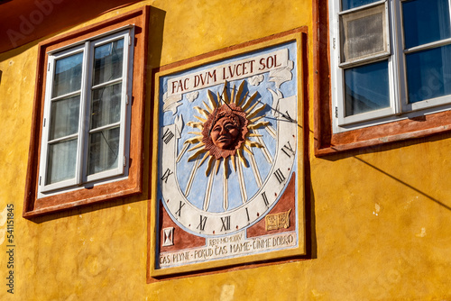 Vintage sundial with latin inscription (fac dum lucet sol) on the facade of an old house, Kolin, Czech republic, Europe